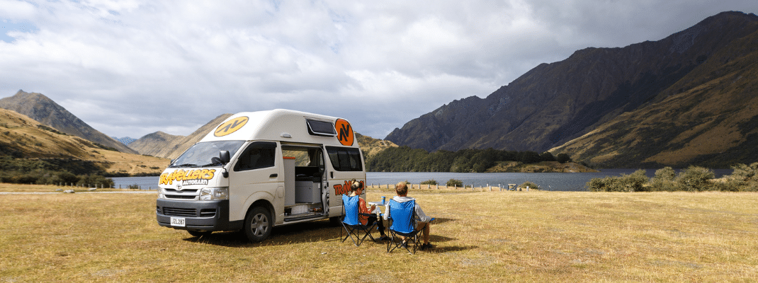 People sitting on camping chairs next to campervan in New Zealand 