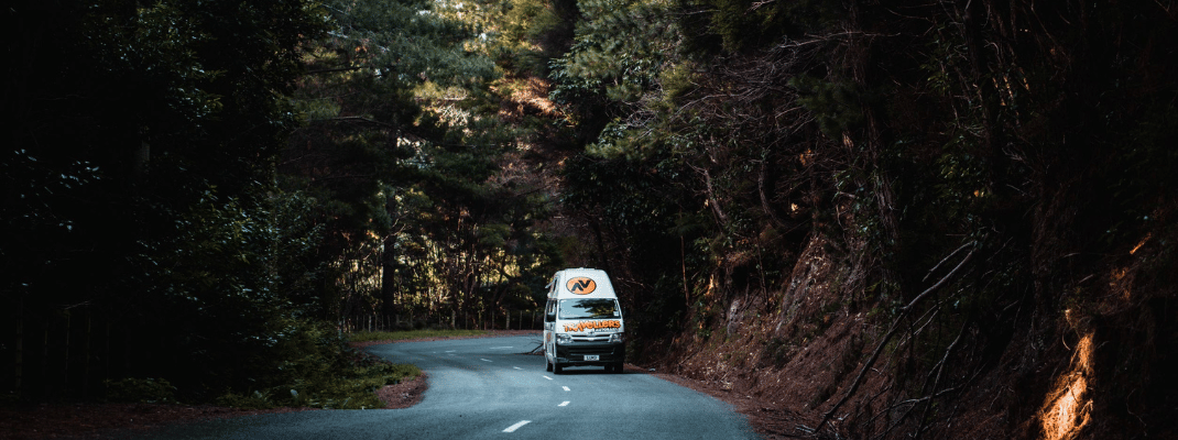 Campervan driving on road through forest