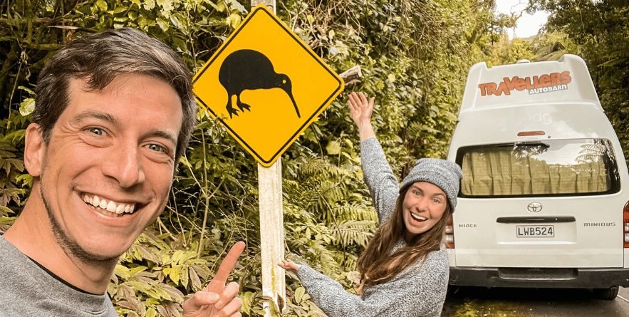 People standing next to Kiwi sign in New Zealand