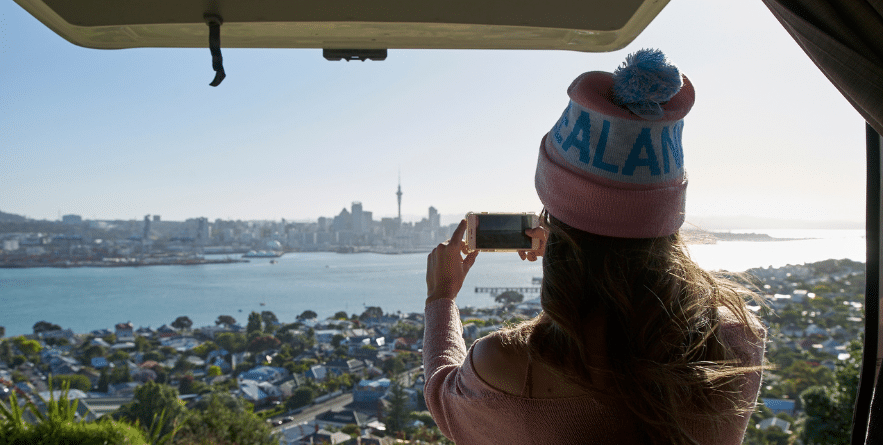 Person in campervan taking a photo of Auckland cityscape