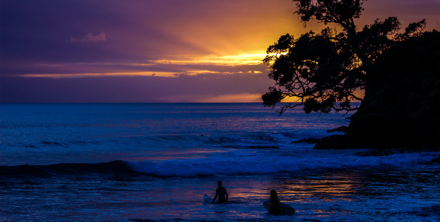 Heading out to surf as the sun rises. Waipu Cove, New Zealand